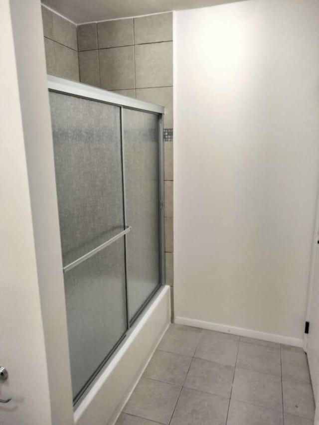 bathroom featuring tile patterned floors and bath / shower combo with glass door