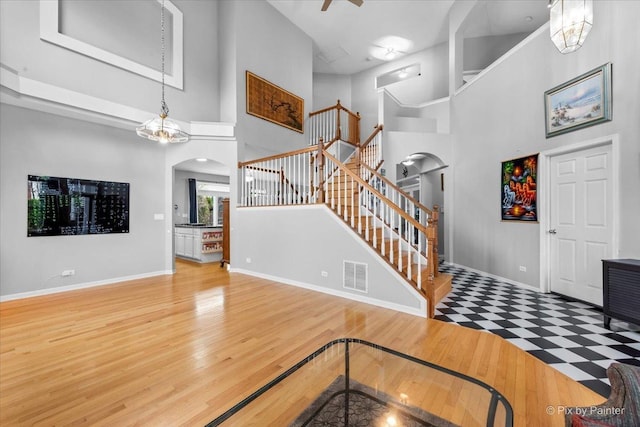 entryway featuring hardwood / wood-style flooring, a towering ceiling, and a notable chandelier