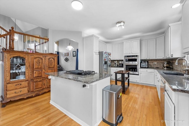 kitchen featuring a kitchen island, sink, white cabinets, decorative backsplash, and stainless steel appliances