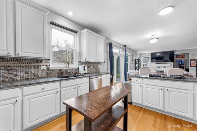 kitchen featuring white cabinetry, dishwasher, sink, and dark stone countertops