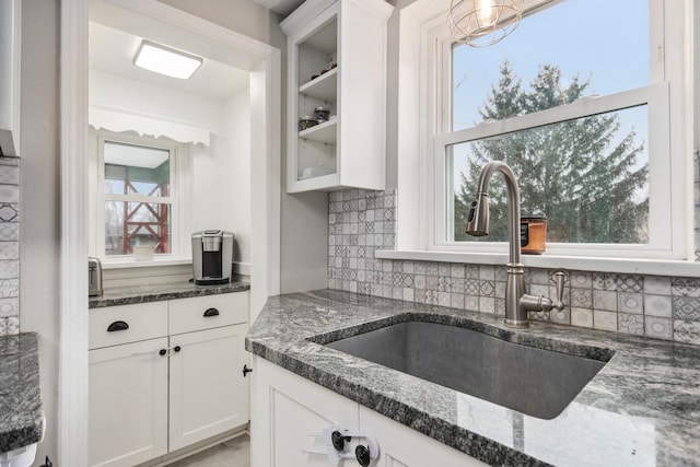 kitchen featuring white cabinets, sink, a wealth of natural light, and dark stone counters