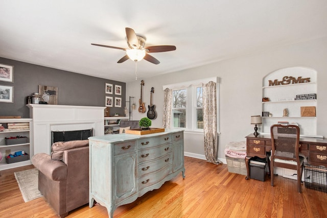 interior space featuring built in shelves, ceiling fan, and light hardwood / wood-style floors