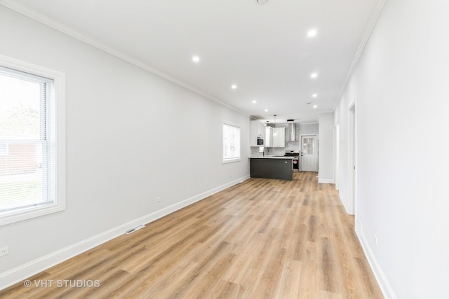 unfurnished living room with crown molding, a healthy amount of sunlight, and light hardwood / wood-style floors