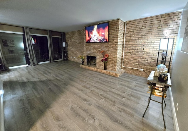 unfurnished living room with a brick fireplace, brick wall, and hardwood / wood-style flooring