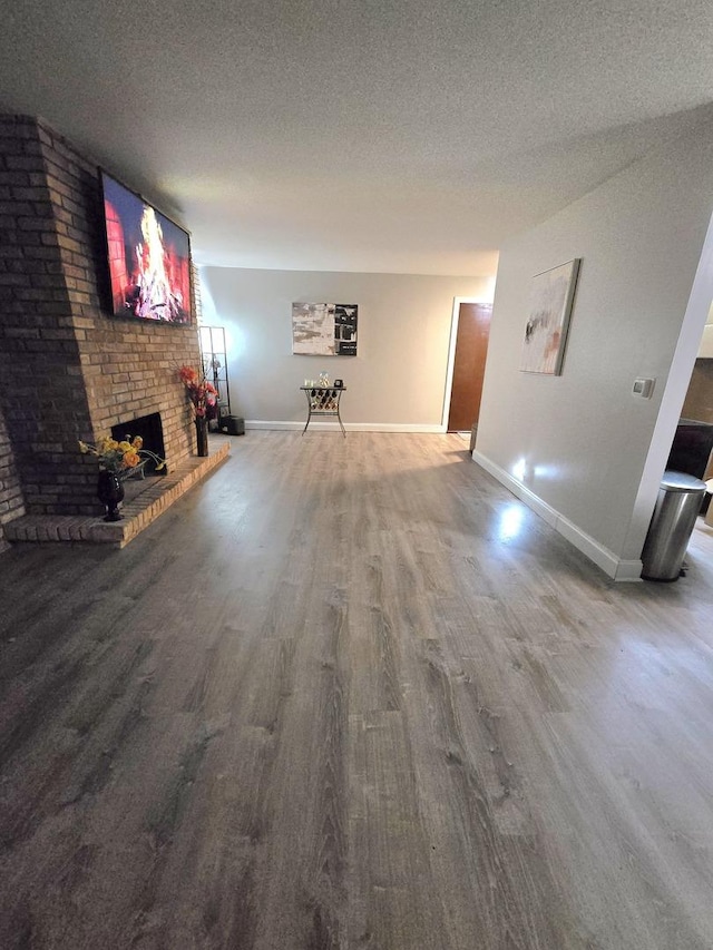 unfurnished living room featuring wood-type flooring, a textured ceiling, and a fireplace