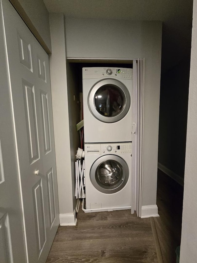 laundry room with dark hardwood / wood-style flooring and stacked washer and clothes dryer