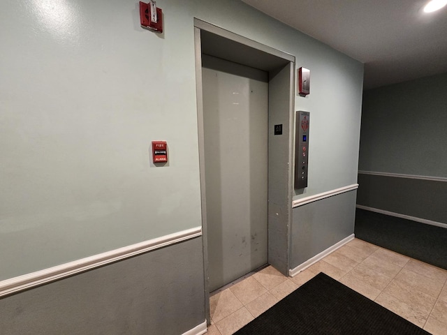 hallway featuring elevator and light tile patterned flooring