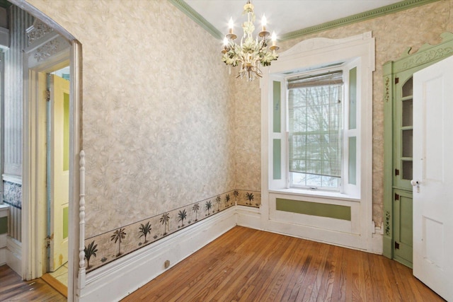 interior space featuring plenty of natural light, an inviting chandelier, ornamental molding, and hardwood / wood-style flooring