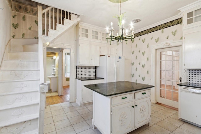 kitchen featuring white cabinets, a kitchen island, white appliances, and ornamental molding