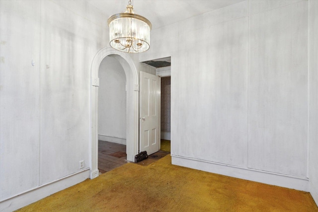 carpeted spare room with an inviting chandelier