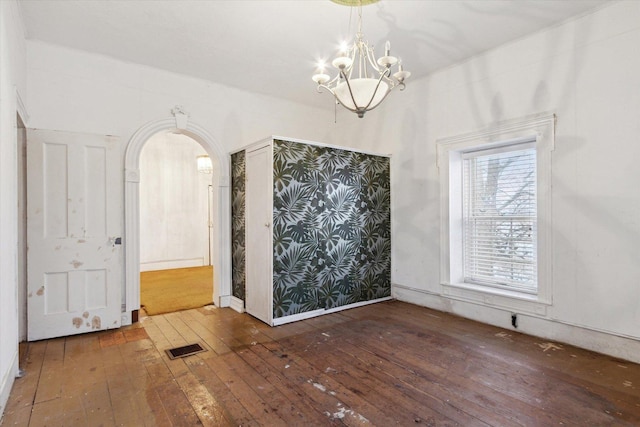 unfurnished dining area with a notable chandelier and dark hardwood / wood-style floors