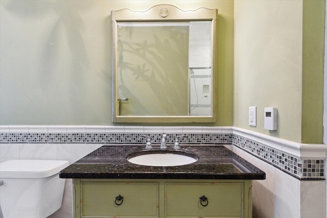 bathroom featuring vanity, toilet, and tile walls