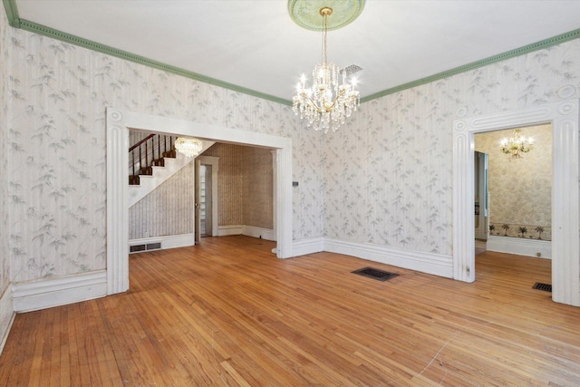 unfurnished dining area with wood-type flooring, ornamental molding, and an inviting chandelier