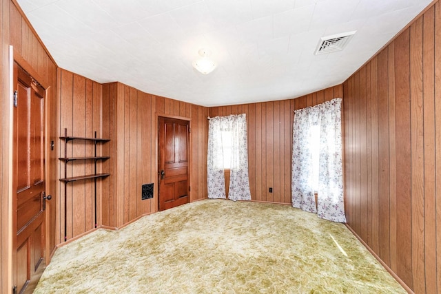 carpeted empty room with wood walls