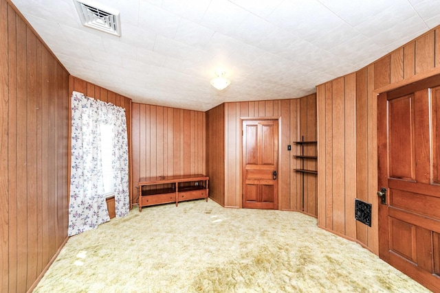 unfurnished room with wood walls and carpet