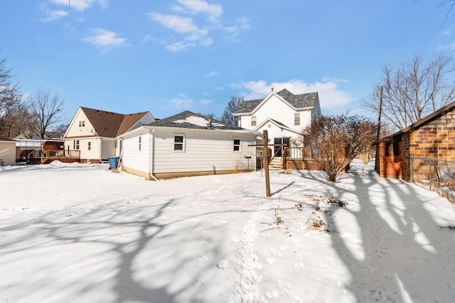 snow covered rear of property with a wooden deck