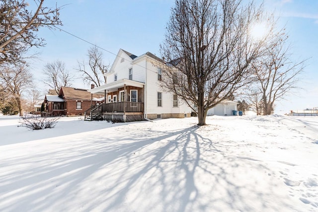 snow covered back of property with covered porch