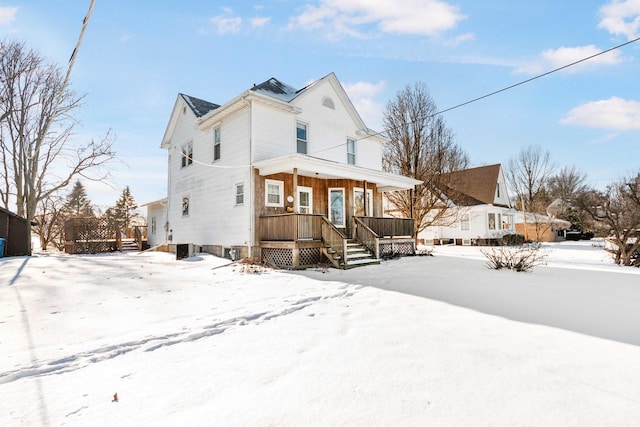 snow covered back of property with a porch