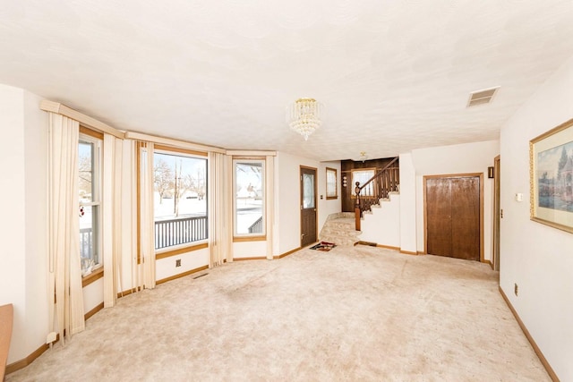 spare room with carpet floors, plenty of natural light, and a chandelier