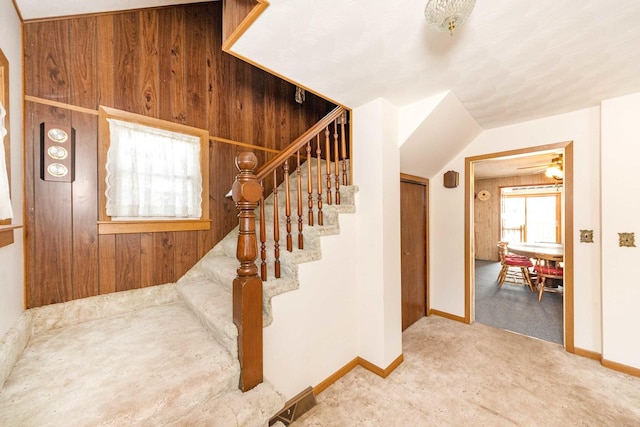 stairs featuring vaulted ceiling, carpet, and wood walls