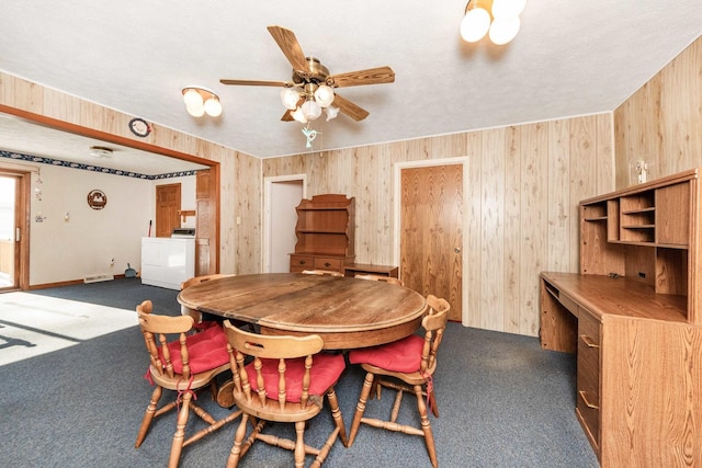 carpeted dining area featuring ceiling fan, washer / clothes dryer, a textured ceiling, and wood walls