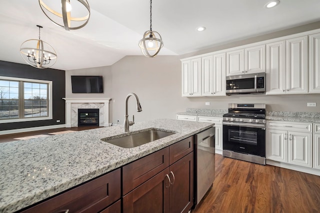 kitchen with sink, decorative light fixtures, lofted ceiling, a fireplace, and appliances with stainless steel finishes