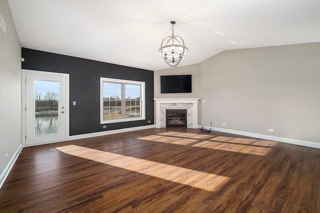 unfurnished living room with a fireplace, dark hardwood / wood-style flooring, lofted ceiling, and a notable chandelier