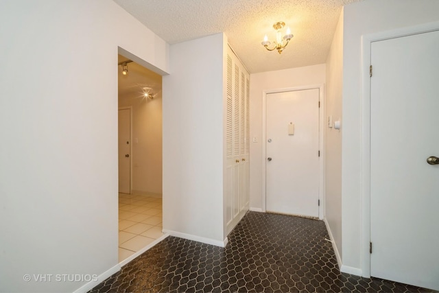 hallway featuring a textured ceiling and a notable chandelier