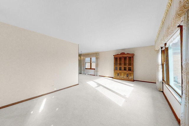 carpeted spare room featuring a chandelier