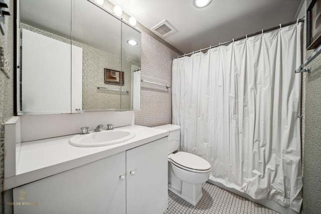 bathroom with toilet, vanity, and tile patterned floors