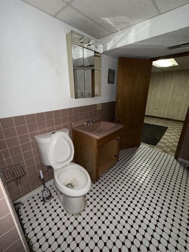 bathroom with vanity, tile walls, and toilet