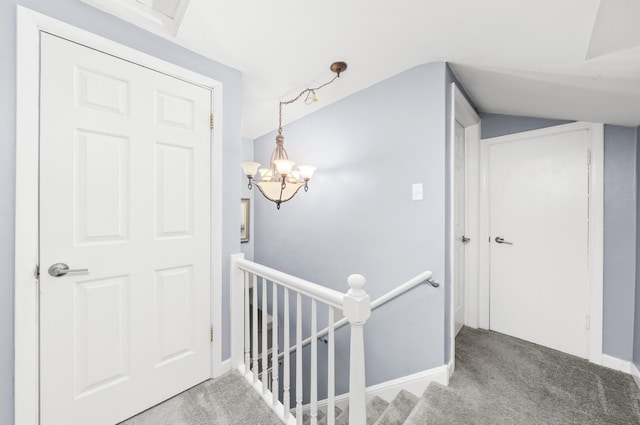 hallway featuring carpet flooring, lofted ceiling, and an inviting chandelier