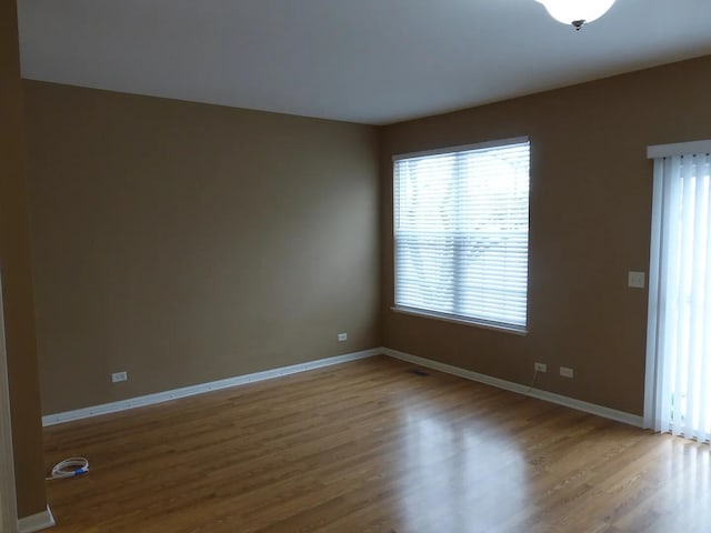 empty room with plenty of natural light and hardwood / wood-style flooring