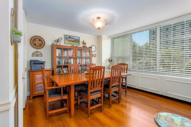 dining area with wood-type flooring and ornamental molding