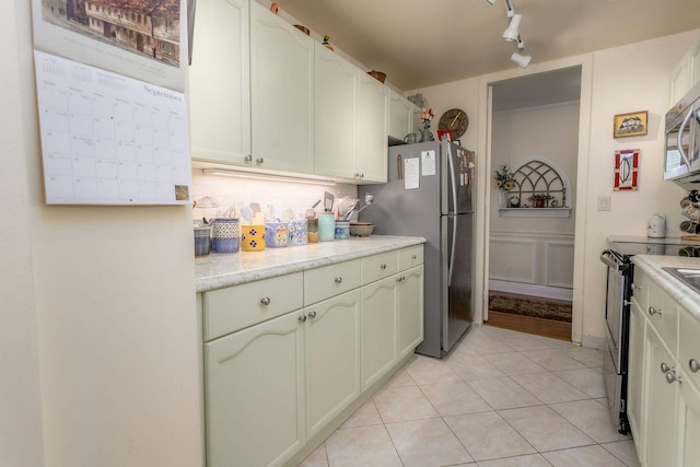 kitchen featuring light tile patterned floors, stainless steel appliances, track lighting, and white cabinetry