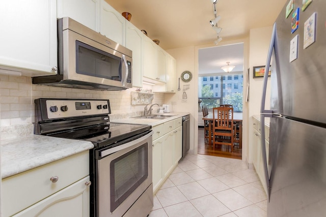 kitchen with appliances with stainless steel finishes, white cabinetry, light tile patterned floors, and sink