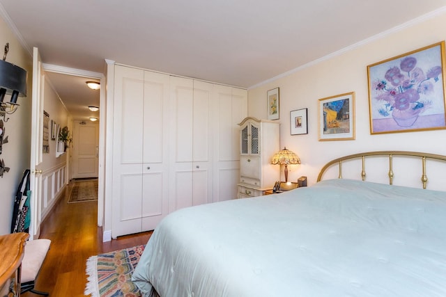 bedroom featuring ornamental molding, a closet, and dark wood-type flooring