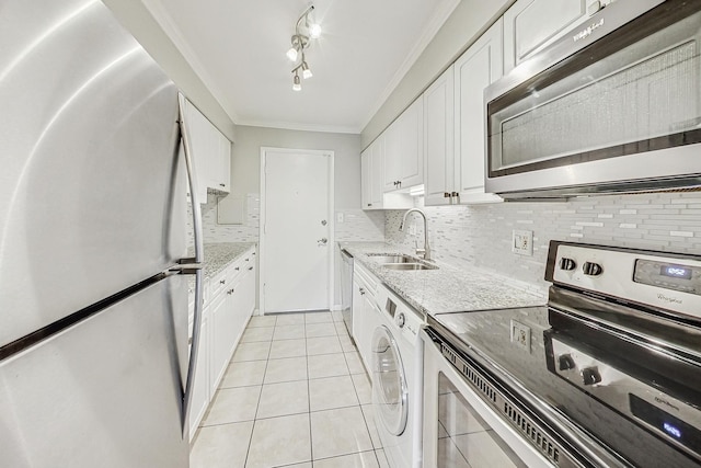 kitchen featuring rail lighting, sink, washer / dryer, white cabinetry, and stainless steel appliances