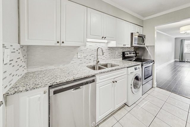 kitchen featuring appliances with stainless steel finishes, ornamental molding, sink, washer / dryer, and white cabinetry