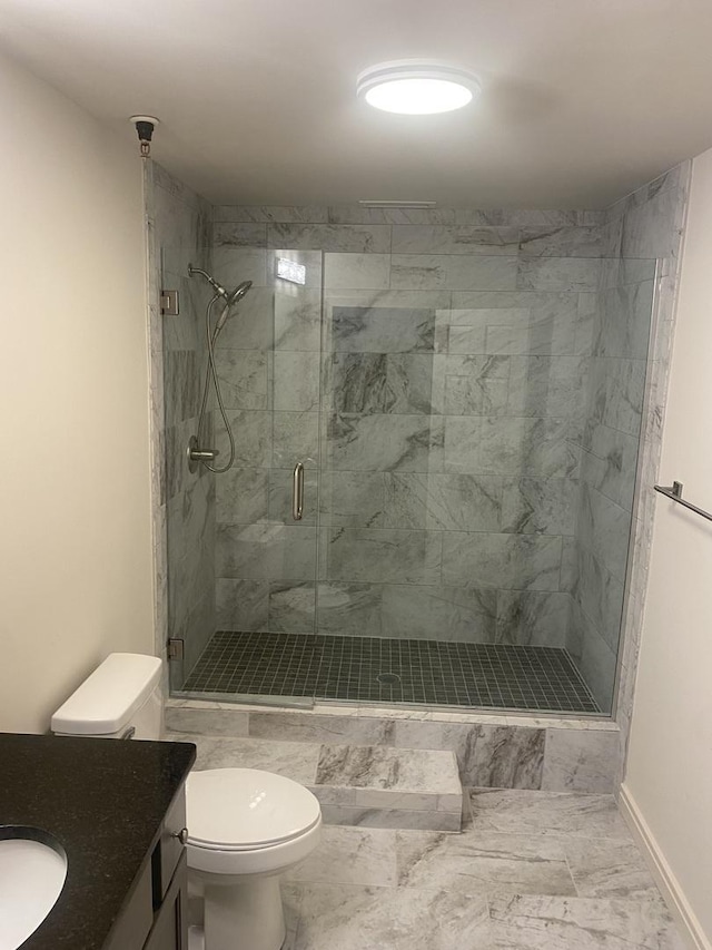 full bathroom with toilet, marble finish floor, a stall shower, baseboards, and vanity