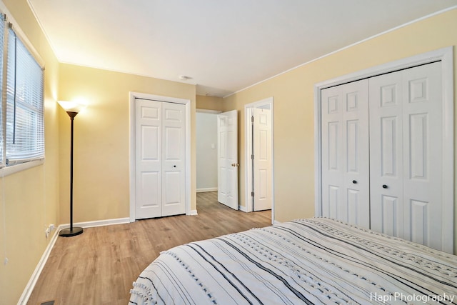 bedroom with light wood-type flooring and two closets