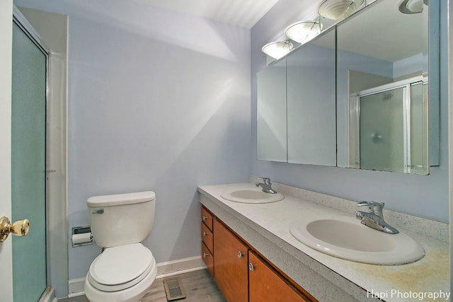 bathroom with vanity, a shower with shower door, and toilet