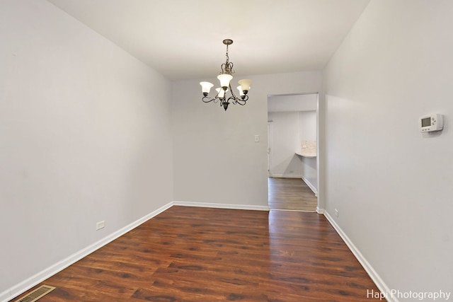 unfurnished dining area with dark hardwood / wood-style flooring and an inviting chandelier