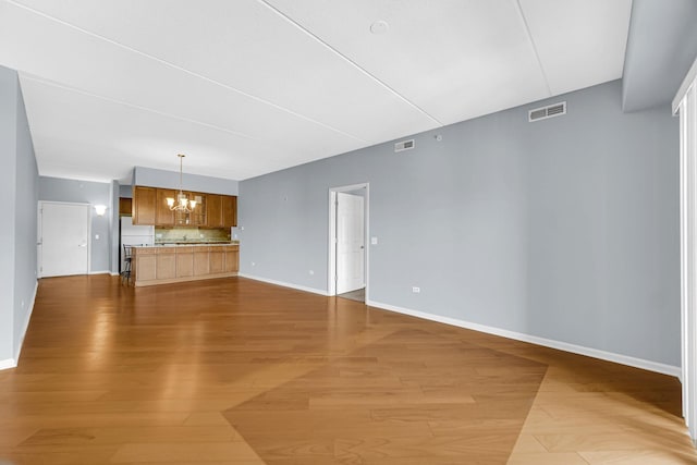 unfurnished living room with wood-type flooring and a notable chandelier