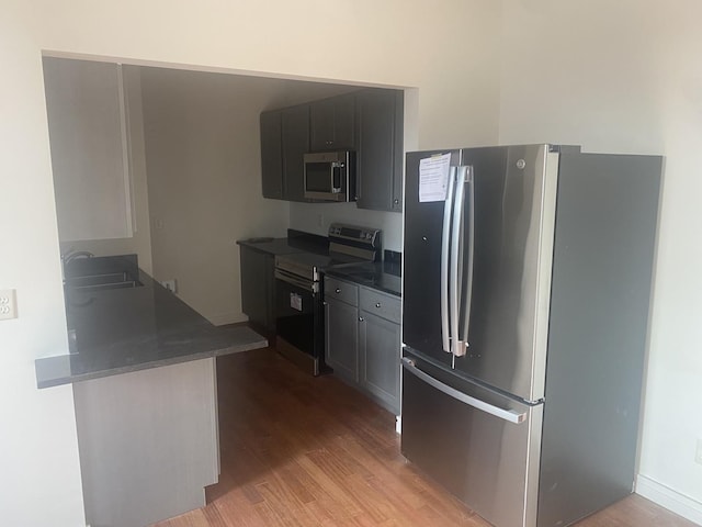 kitchen featuring sink, kitchen peninsula, appliances with stainless steel finishes, and light hardwood / wood-style floors