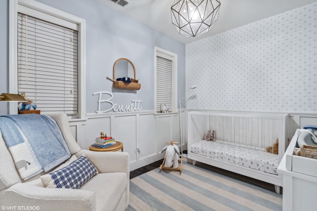 carpeted bedroom with a nursery area and an inviting chandelier