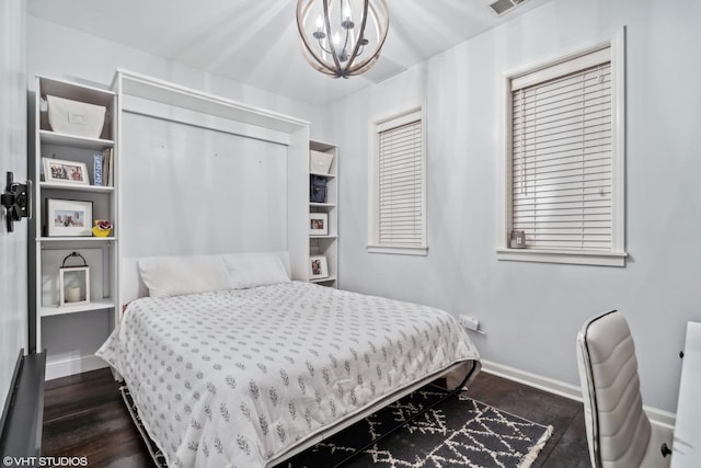 bedroom with a chandelier and dark wood-type flooring