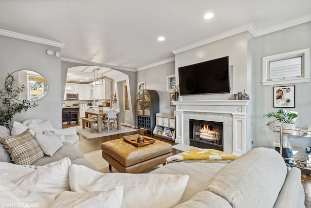 living room with a fireplace, light wood-type flooring, and crown molding