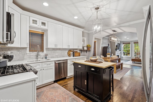 kitchen featuring stainless steel appliances, a kitchen island, white cabinets, and hanging light fixtures