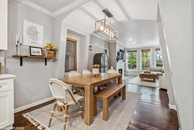 dining space featuring a notable chandelier, ornamental molding, and dark hardwood / wood-style flooring